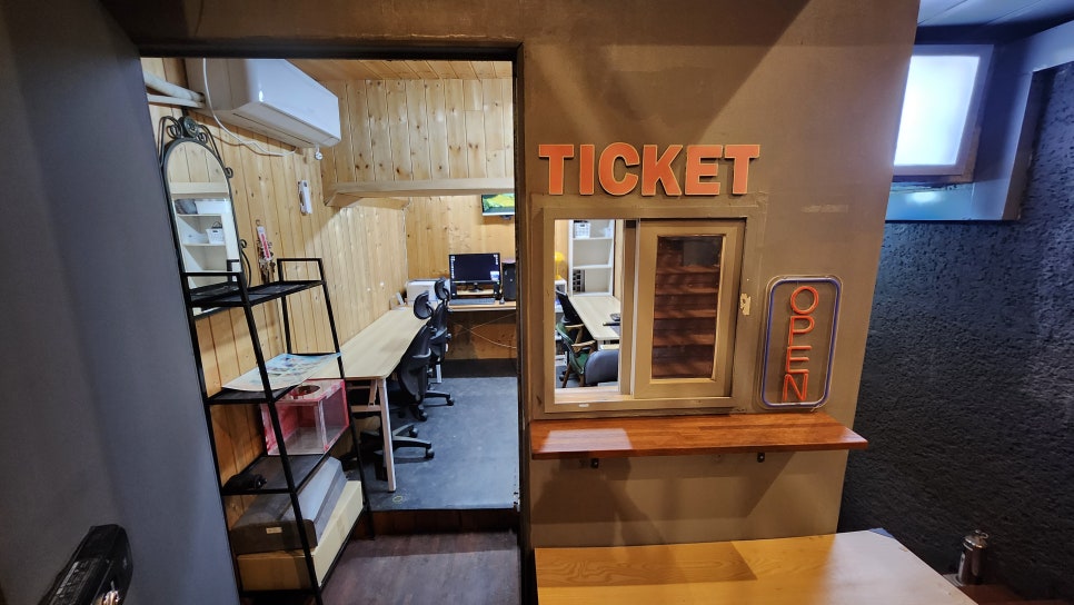온맘씨어터 지하 1층 로비 티켓 부스 — TICKET 사인과 OPEN 네온사인이 있는 매표 창구, 공연·쇼케이스 현장 발권 및 관객 입장 안내 공간